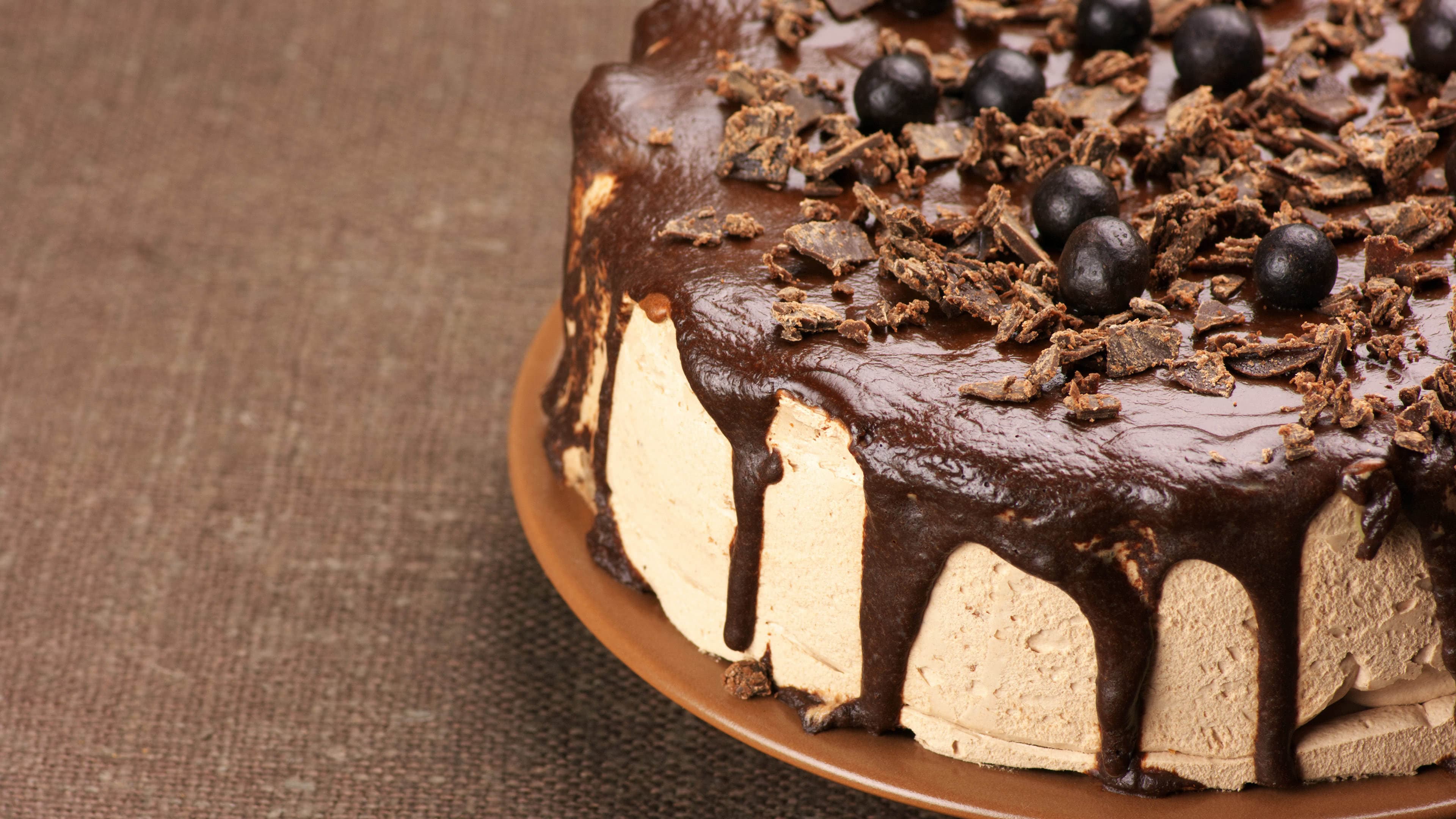 Chocolate cake with mocha frosting, dark ganache drips, and chocolate garnish on a ceramic plate